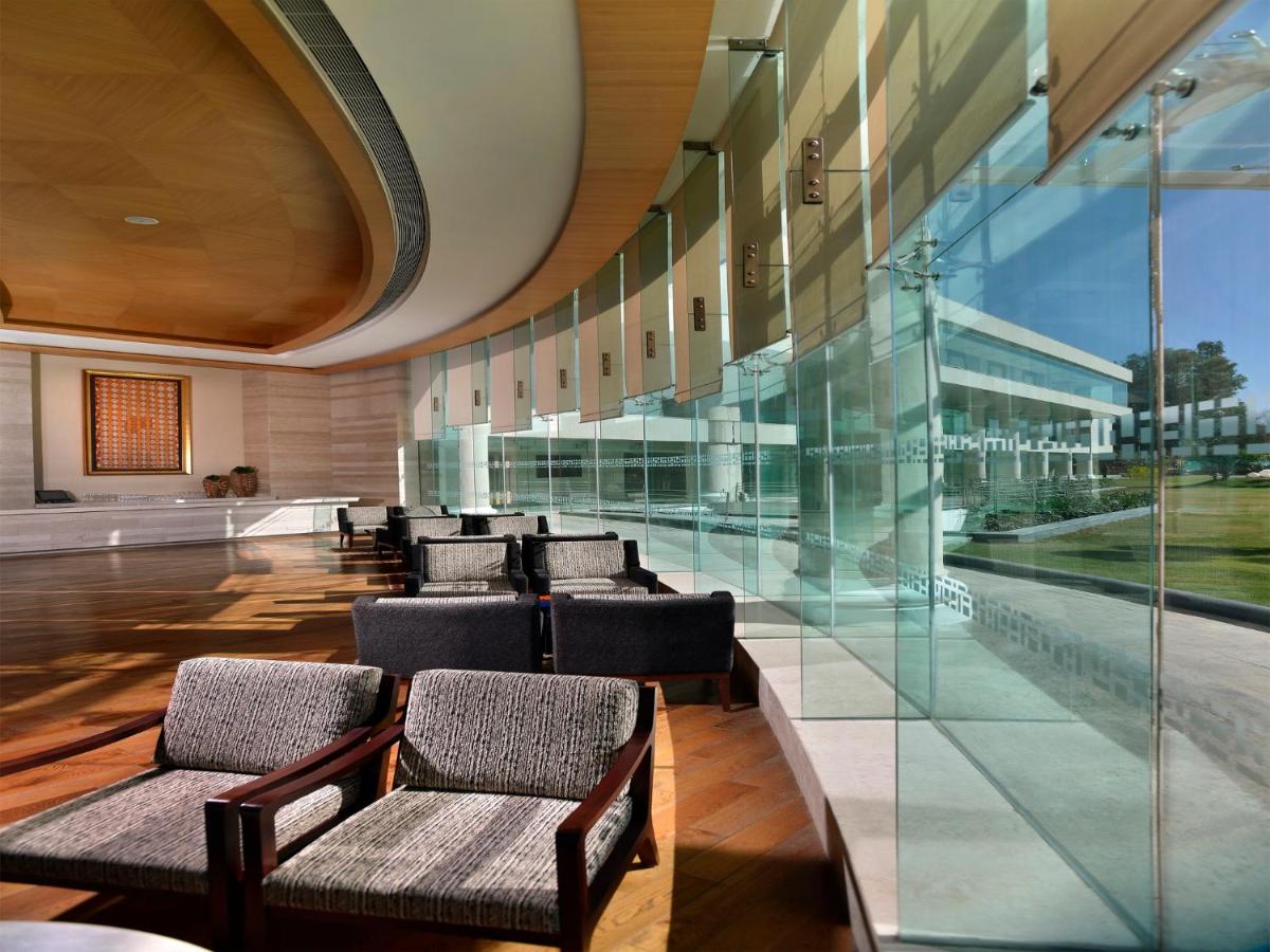 a row of chairs in a room with glass walls at The Lalit Chandigarh in Chandīgarh