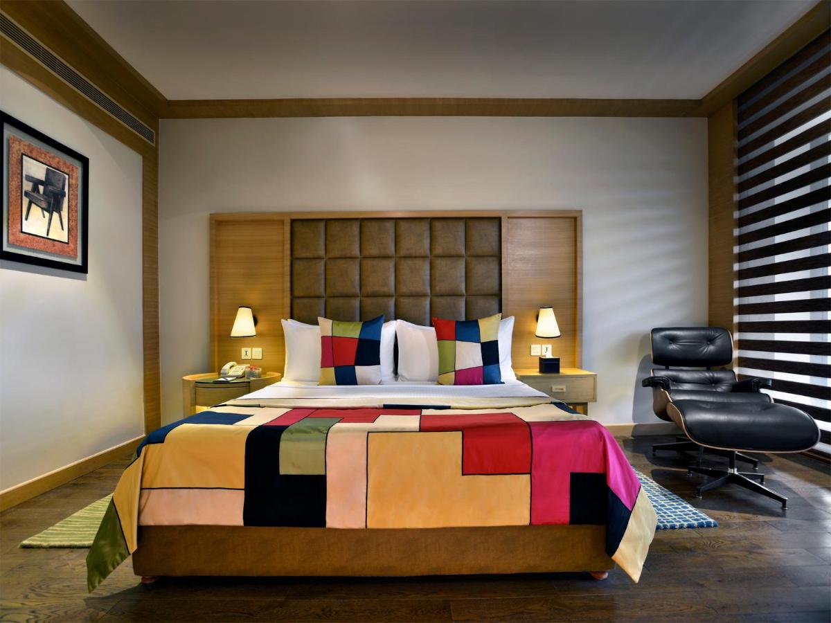 a bedroom with a large bed and a chair at The Lalit Chandigarh in Chandīgarh