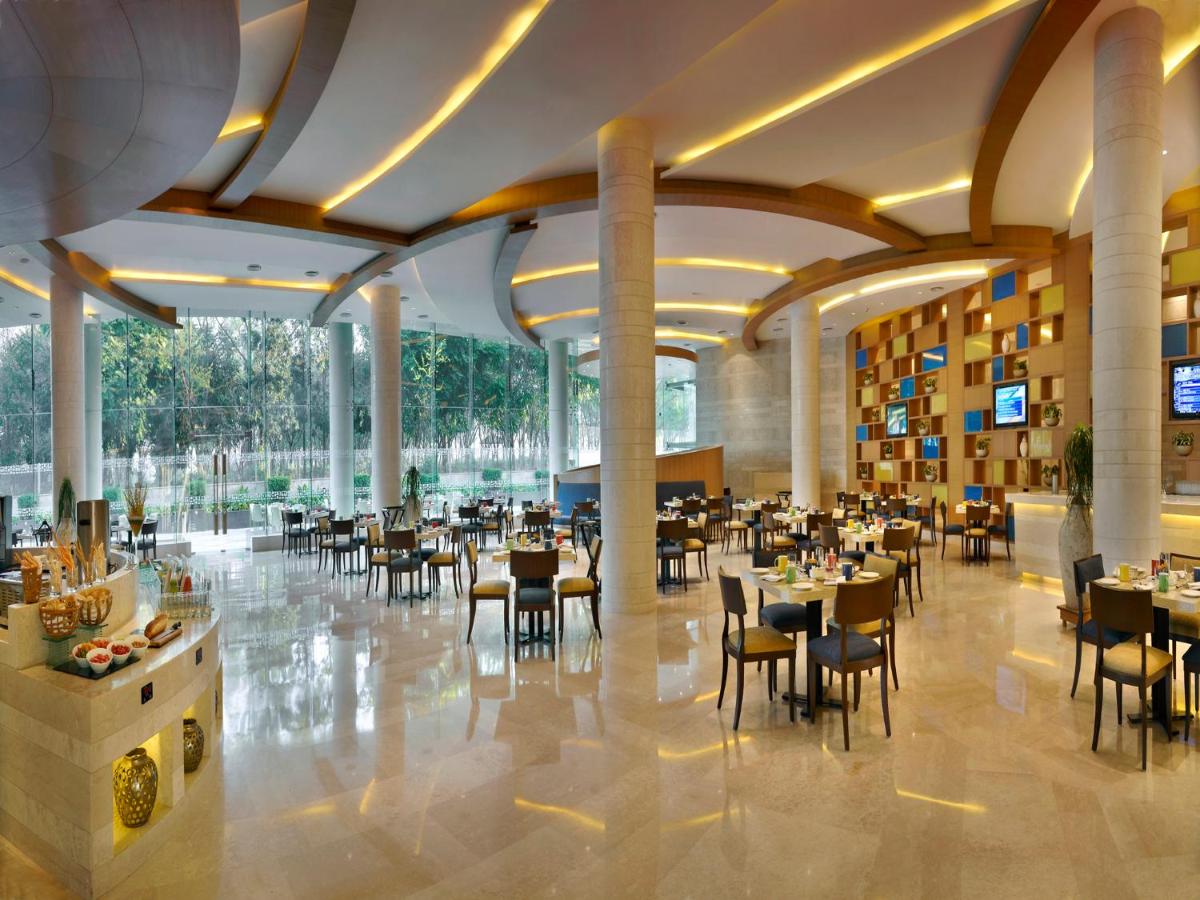 a restaurant with tables and chairs in a building at The Lalit Chandigarh in Chandīgarh