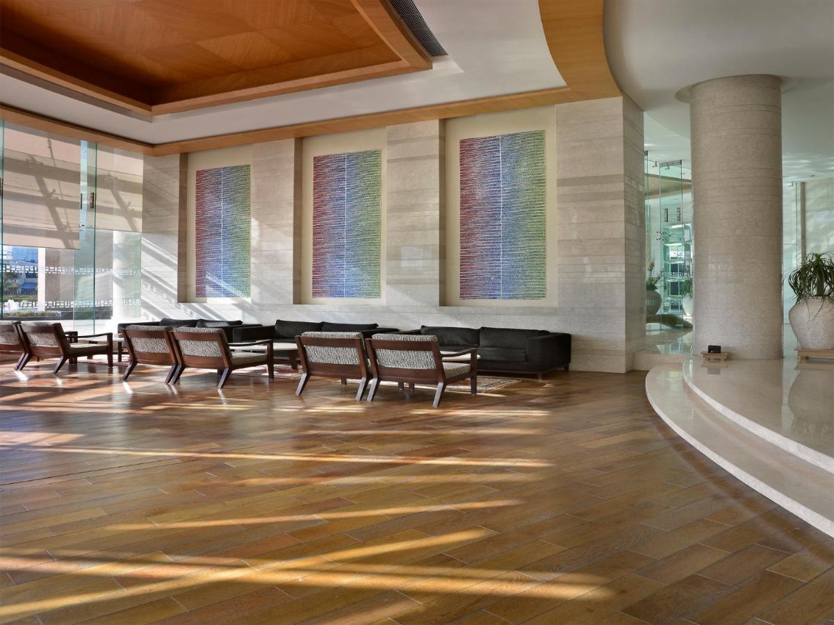 a lobby with chairs and a table and windows at The Lalit Chandigarh in Chandīgarh