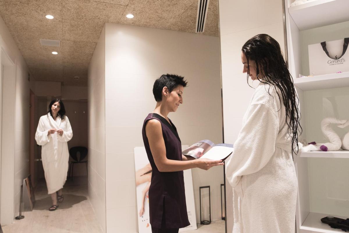 una mujer en un camerino mirando a una mujer en un espejo en Hotel Pompaelo Plaza del Ayuntamiento & Spa, en Pamplona