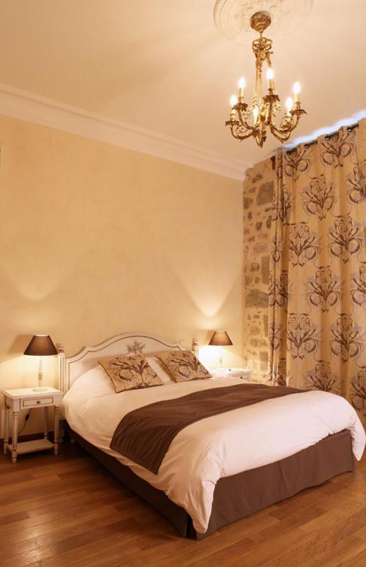 une chambre avec un grand lit et un lustre dans l'établissement Domaine Saint-Roch Hotel Spa, à Salzuit
