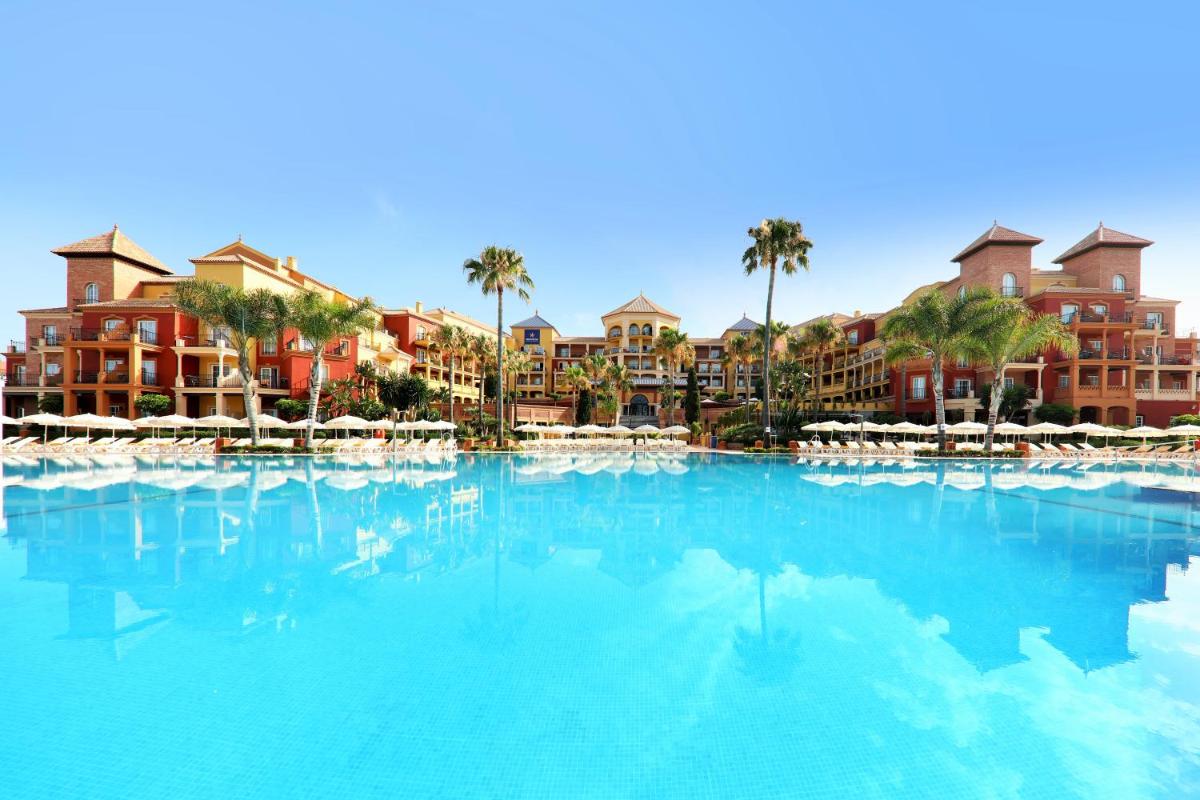 Una gran piscina con palmeras y edificios. en Iberostar Waves Málaga Playa, en Torrox Costa