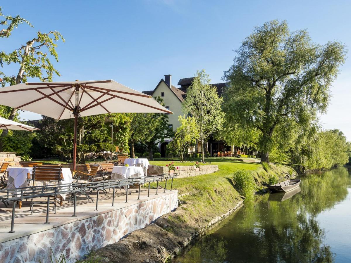 un restaurant avec des tables et un parasol à côté d'une rivière dans l'établissement Hotel des Berges, Restaurant Gastronomique & Spa, à Illhaeusern