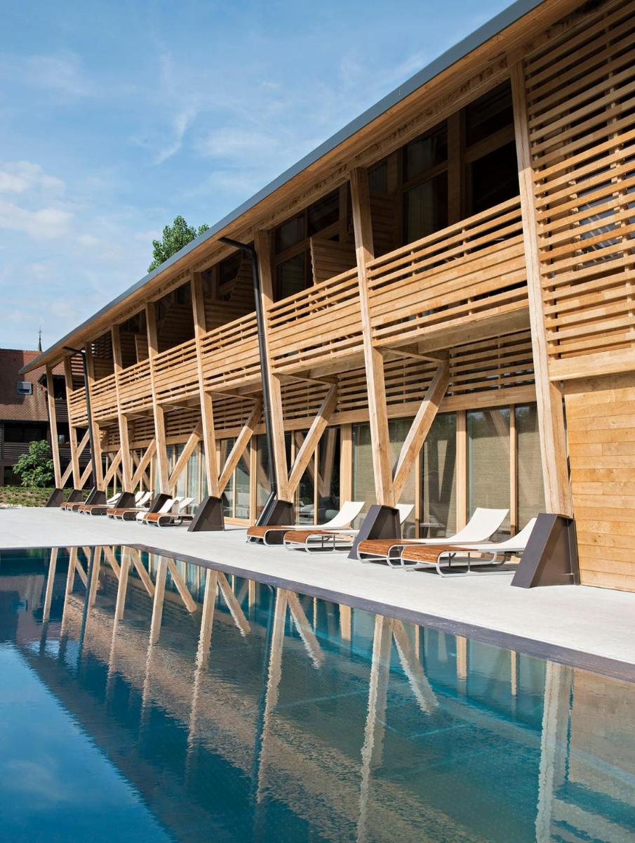 - un bâtiment avec une piscine et des chaises longues dans l'établissement Hotel des Berges, Restaurant Gastronomique & Spa, à Illhaeusern