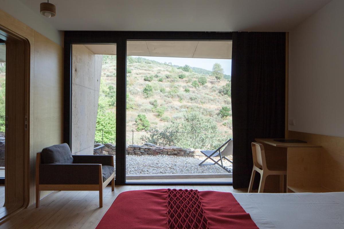 um quarto com uma cama e uma grande janela de vidro em Colmeal Countryside Hotel em Figueira de Castelo Rodrigo mais 86 fotografias