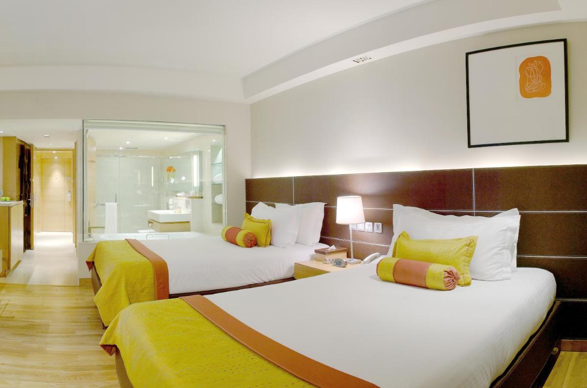 a hotel room with two beds and a bathroom at The LaLiT New Delhi in New Delhi