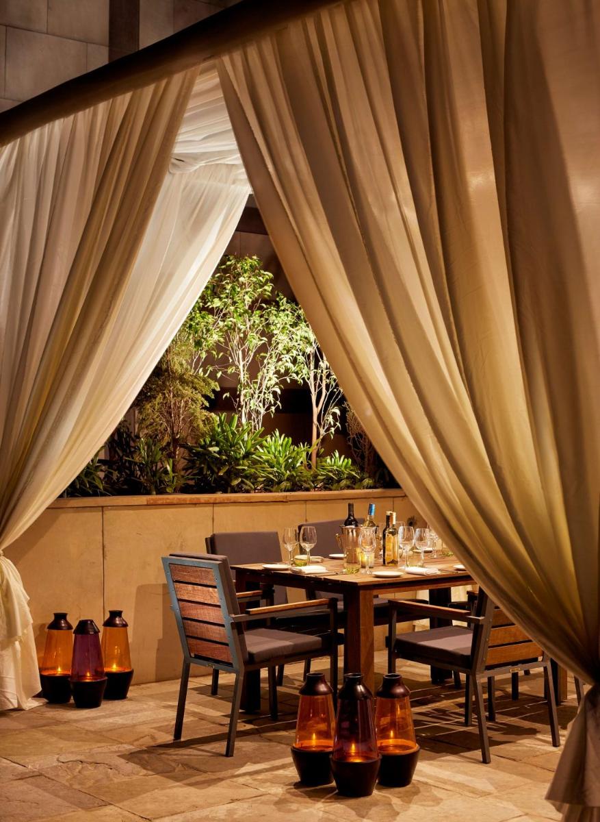 a dining table and chairs in a room with curtains at Hyatt Regency Chandigarh in Chandīgarh