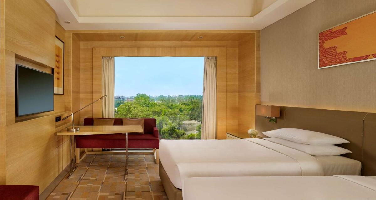 a hotel room with two beds and a desk and a window at Hyatt Regency Chandigarh in Chandīgarh