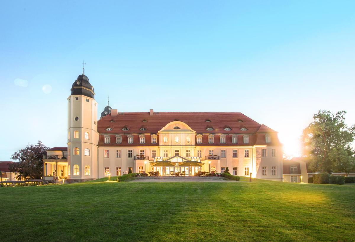 ein großes Gebäude mit einem Turm auf einem Grasfeld in der Unterkunft SCHLOSS Fleesensee in Göhren-Lebbin
