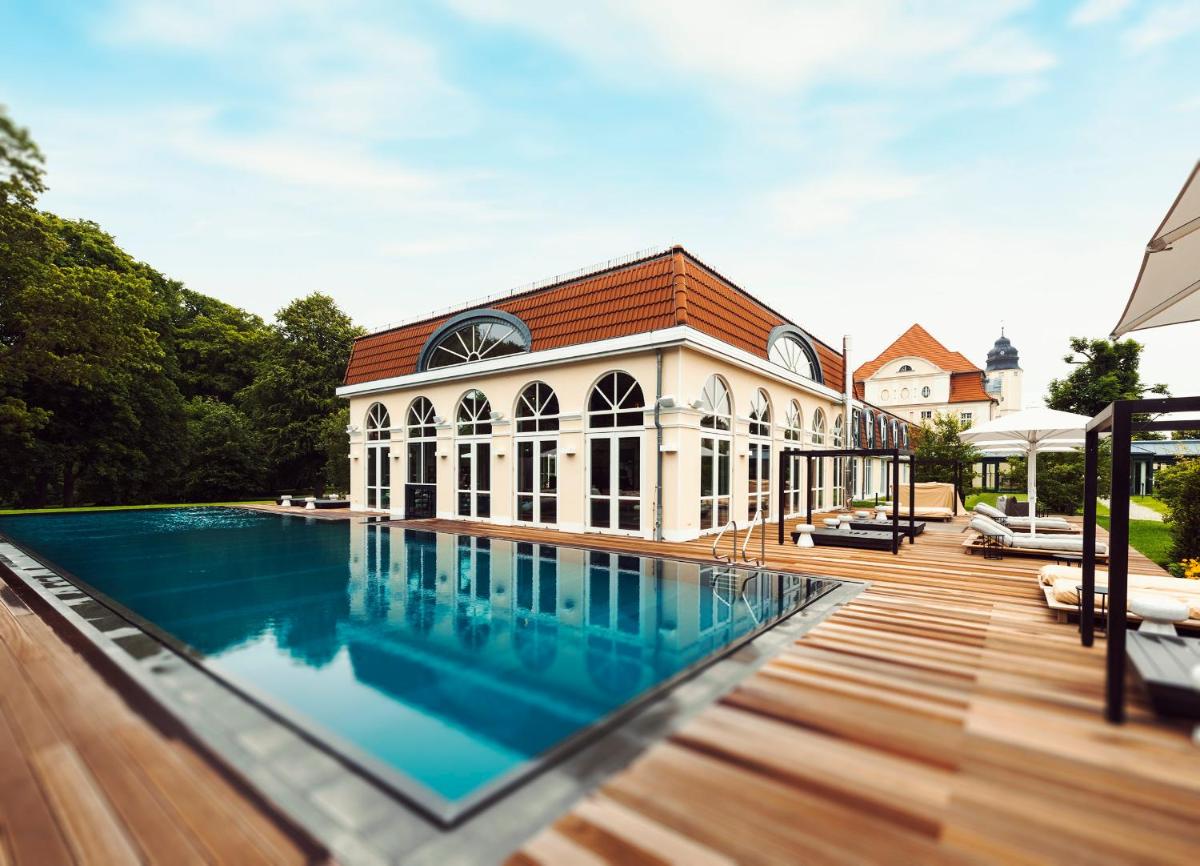 ein Haus mit einem Swimmingpool vor einem Gebäude in der Unterkunft SCHLOSS Fleesensee in Göhren-Lebbin