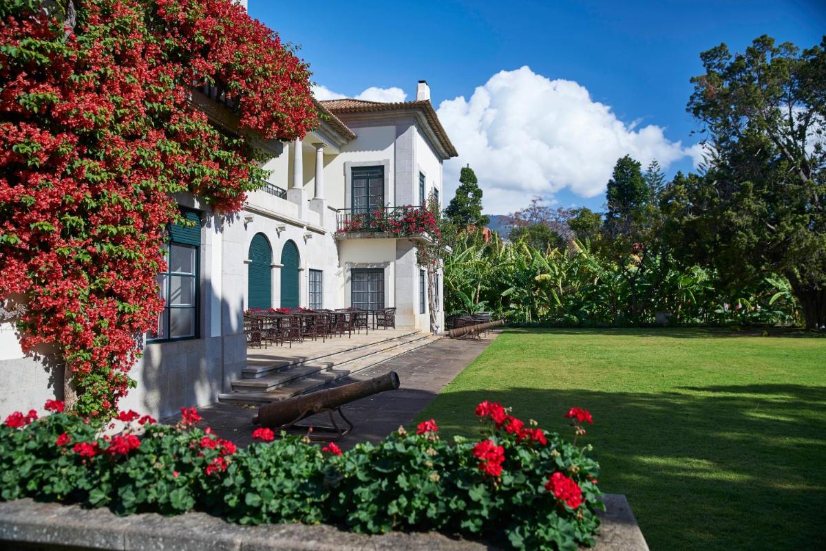 uma casa branca com flores vermelhas no quintal em Quinta da Casa Branca - Small Luxury Hotels of the World no Funchal