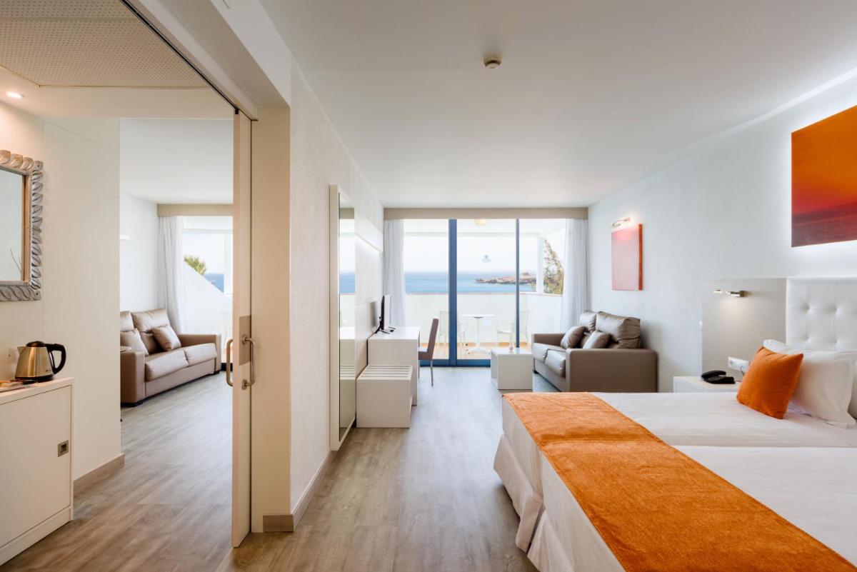Una habitación de hotel con una cama y una sala de estar. en Sandos Papagayo, en Playa Blanca