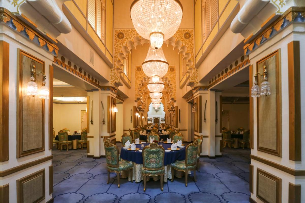 a dining room with a table and chairs and a chandelier at Taj Fateh Prakash Palace Udaipur in Udaipur