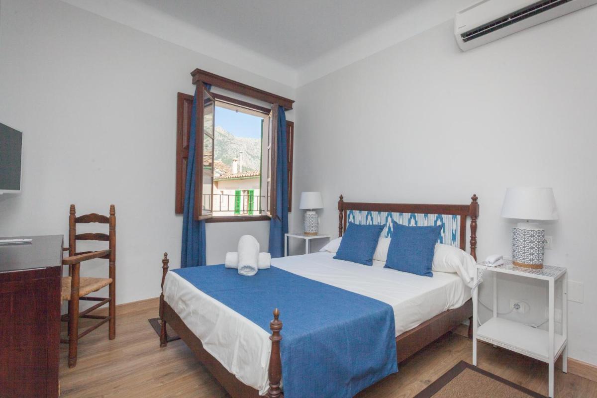 Un dormitorio con una cama con almohadas azules y una ventana. en Hotel El Guía, en Sóller