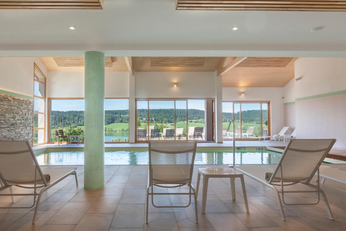 Cette chambre dispose d'une piscine avec des chaises et une table. dans l'établissement Hotel Spa Les Rives Sauvages, à Malbuisson