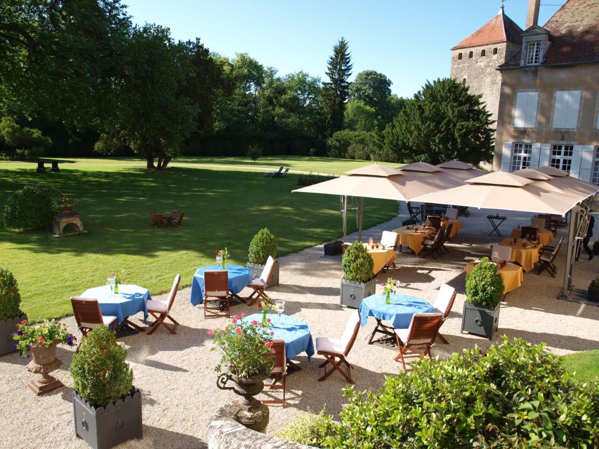 un patio extérieur avec tables, chaises et parasols dans l'établissement Château de Vault de Lugny, à Vault-de-Lugny