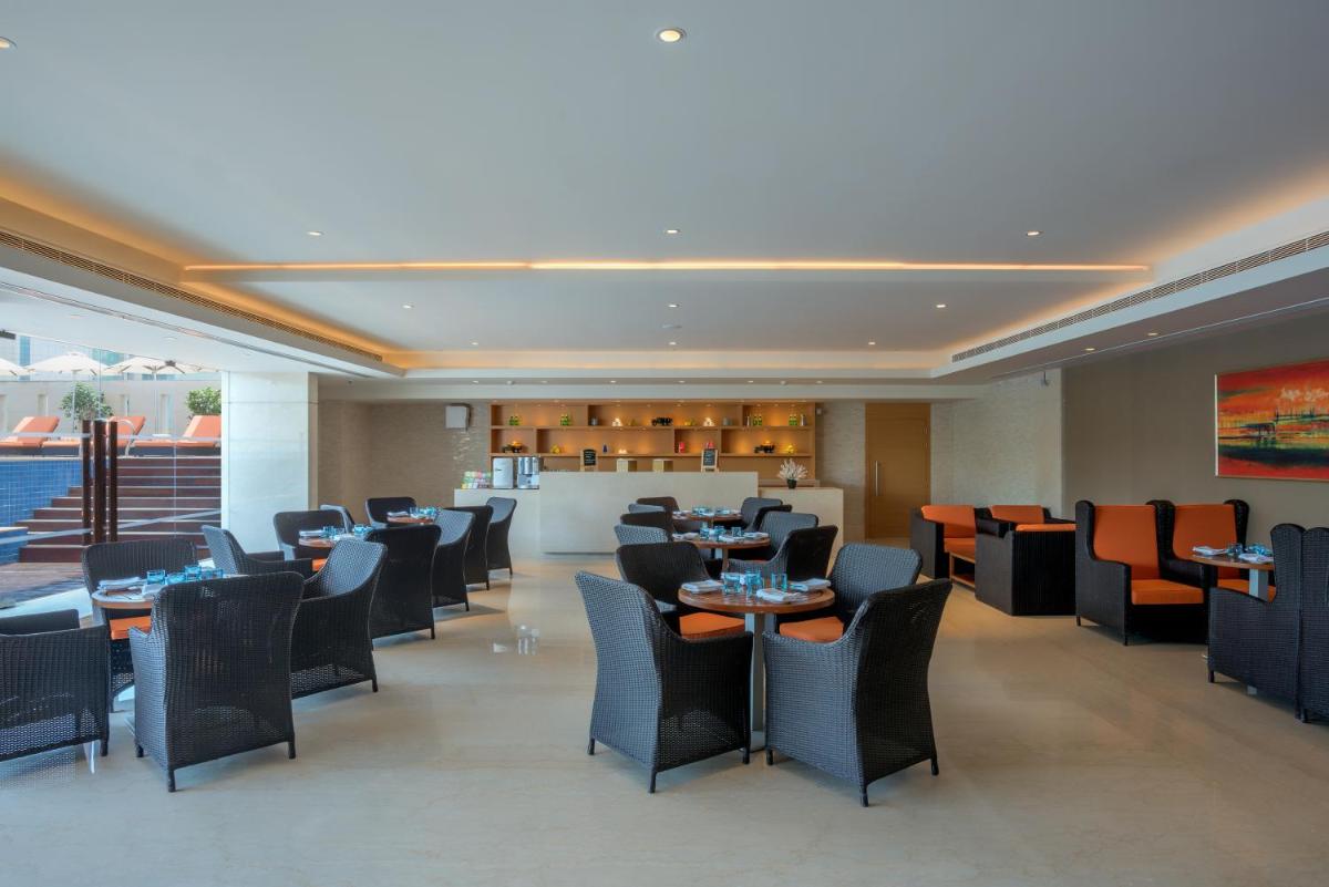 a restaurant with tables and chairs and a bar at Feathers- A Radha Hotel, Chennai in Chennai