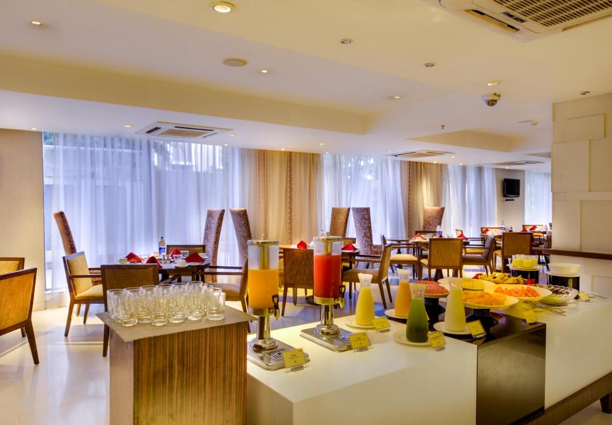 a dining room with tables and chairs and a buffet at Pride Plaza Hotel, Ahmedabad in Ahmedabad