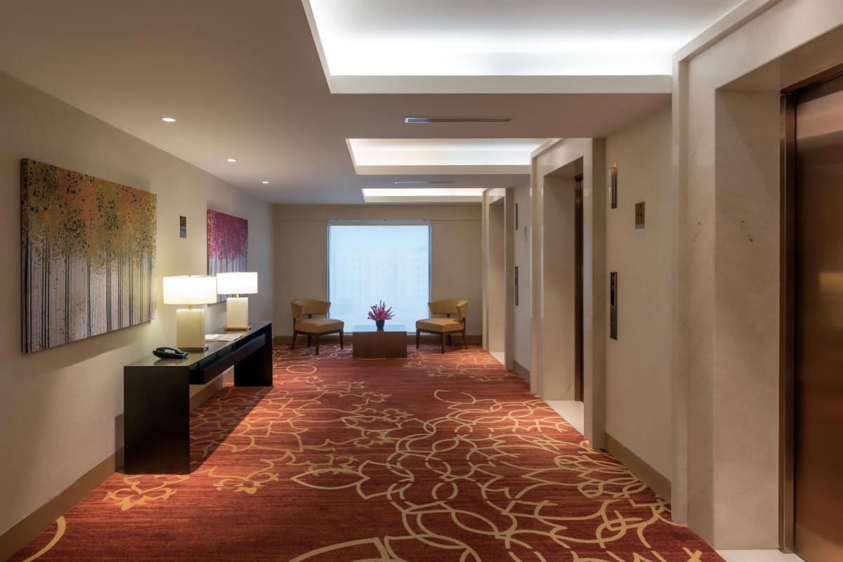 a corridor of a hotel room with a hallway with chairs at Feathers- A Radha Hotel, Chennai in Chennai