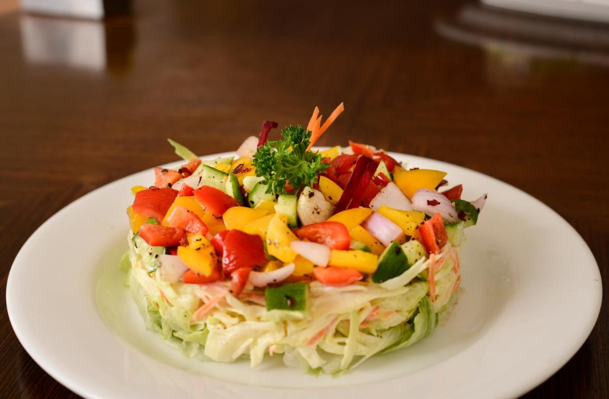 a salad on a white plate on a table at Pride Plaza Hotel, Ahmedabad in Ahmedabad