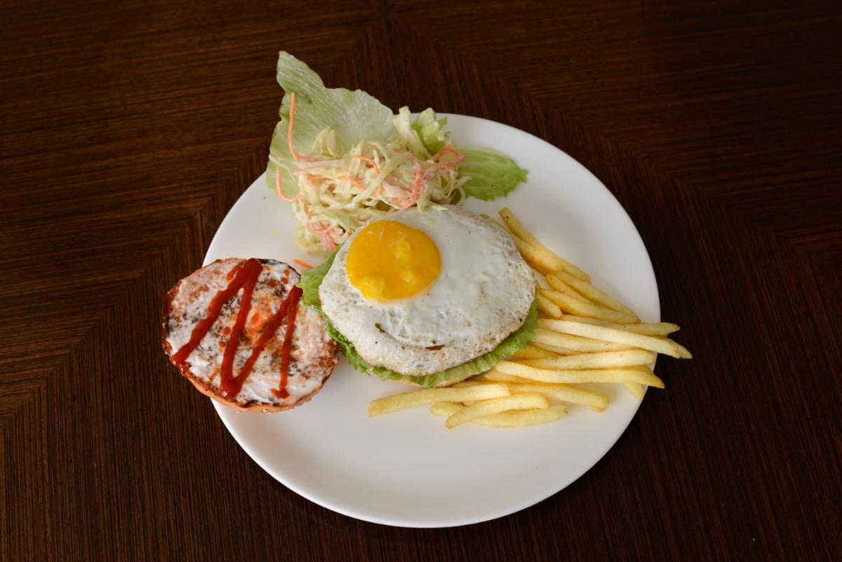 a white plate with an egg sandwich and french fries at Pride Plaza Hotel, Ahmedabad in Ahmedabad