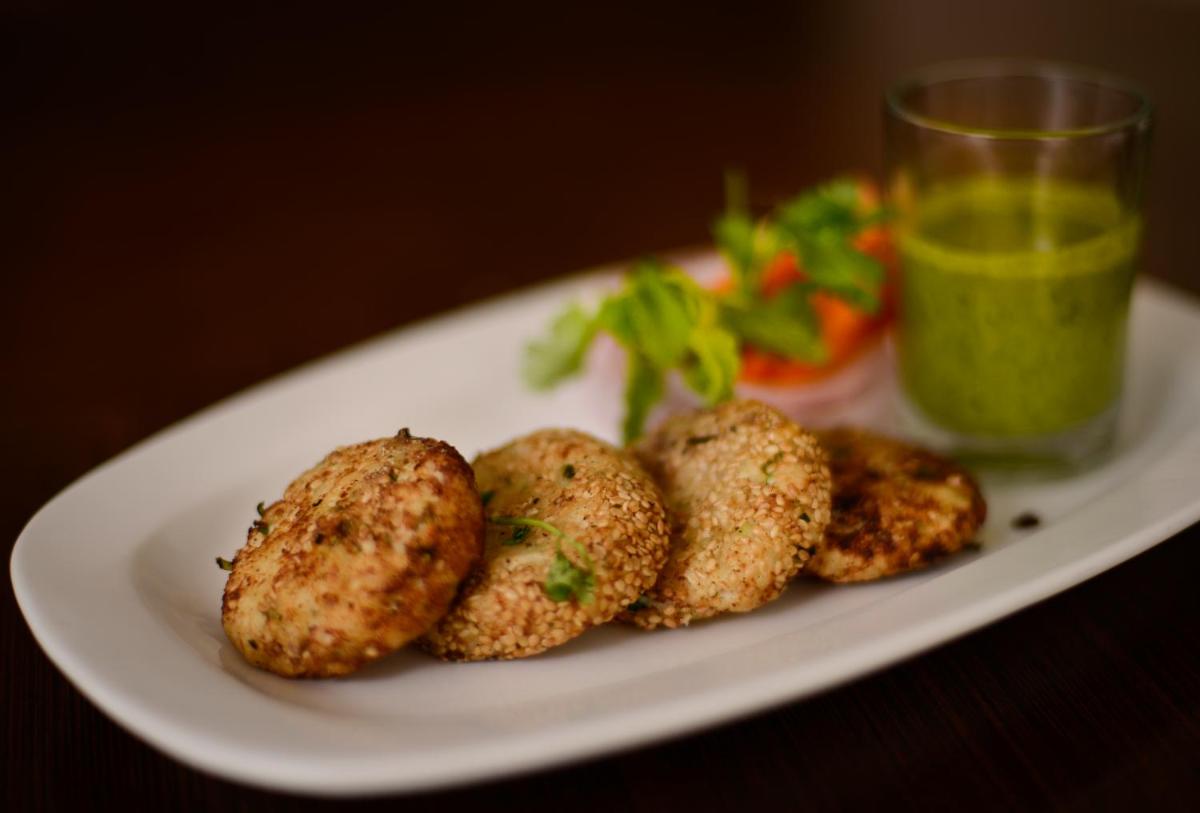 a plate of food with meatballs and a green drink at Pride Plaza Hotel, Ahmedabad in Ahmedabad