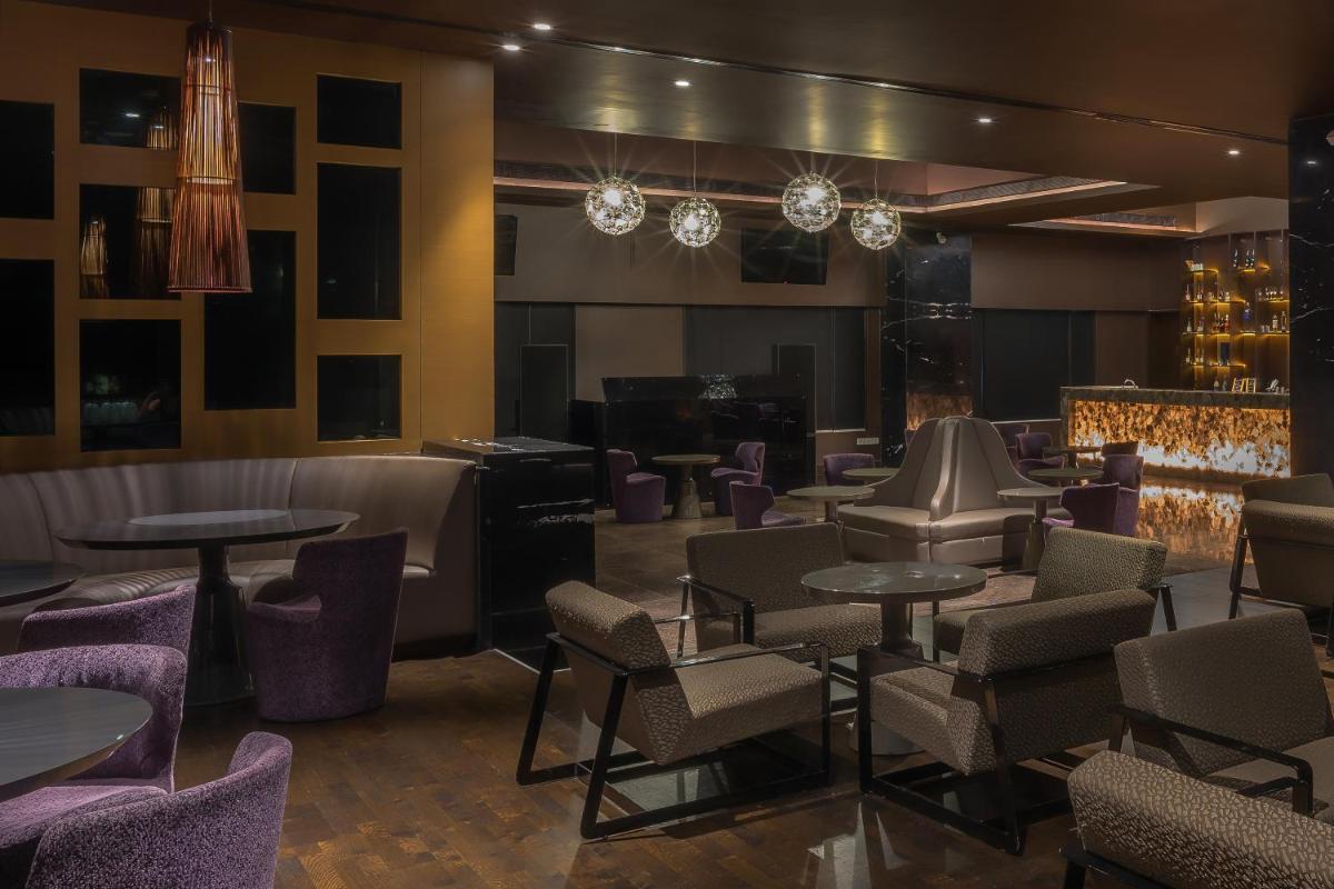 a restaurant with tables and chairs and a bar at Feathers- A Radha Hotel, Chennai in Chennai