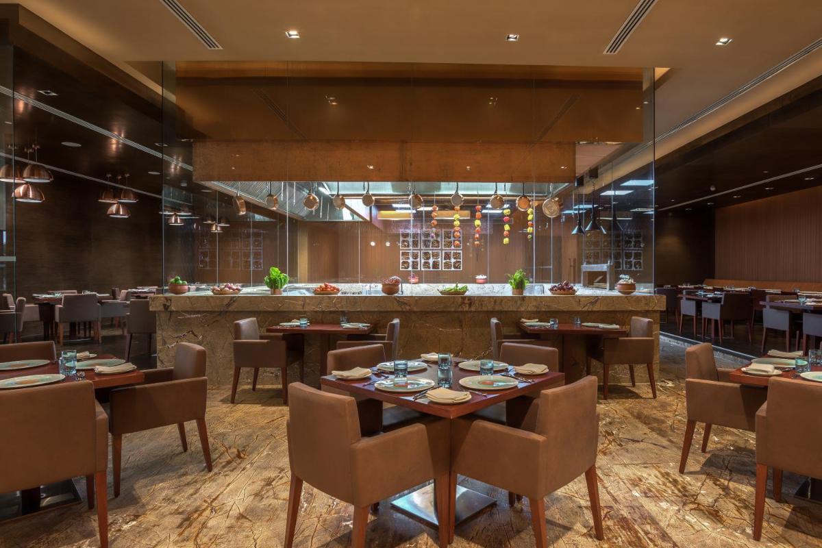 a restaurant with tables and chairs and a bar at Feathers- A Radha Hotel, Chennai in Chennai