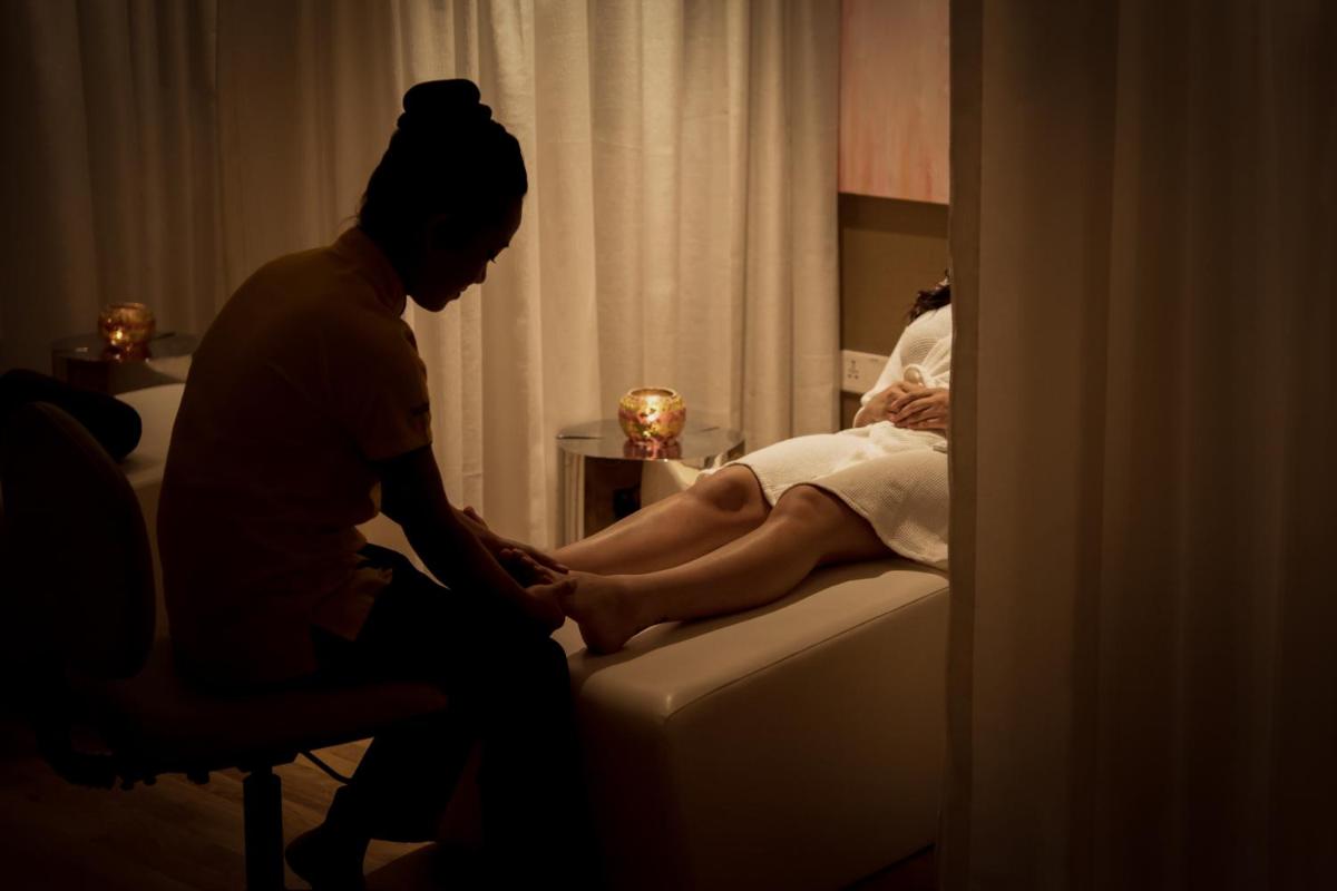 a woman is sitting on a couch with a womaninylinylinylinylinylinyl at Feathers- A Radha Hotel, Chennai in Chennai