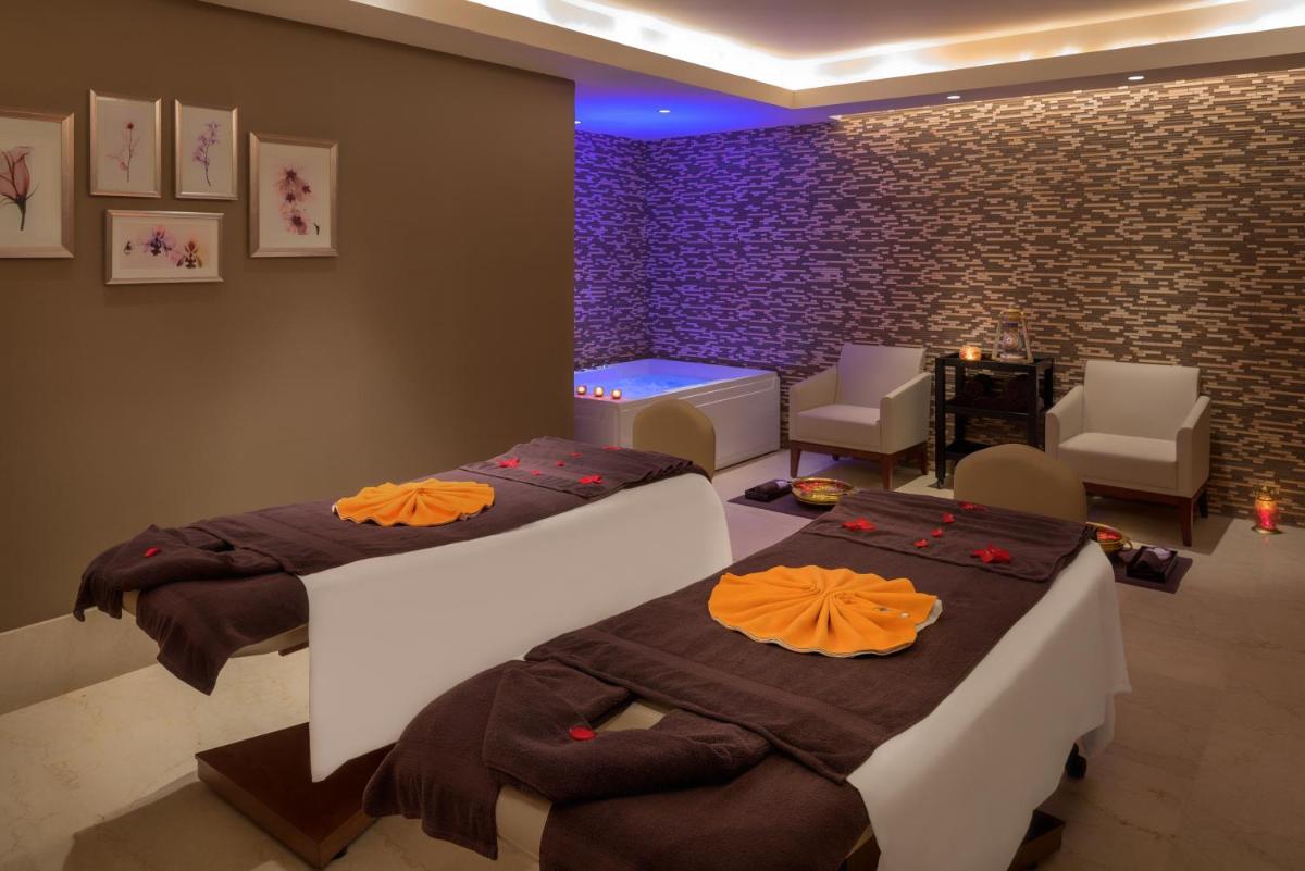 a room with two beds and chairs and purple lighting at Feathers- A Radha Hotel, Chennai in Chennai
