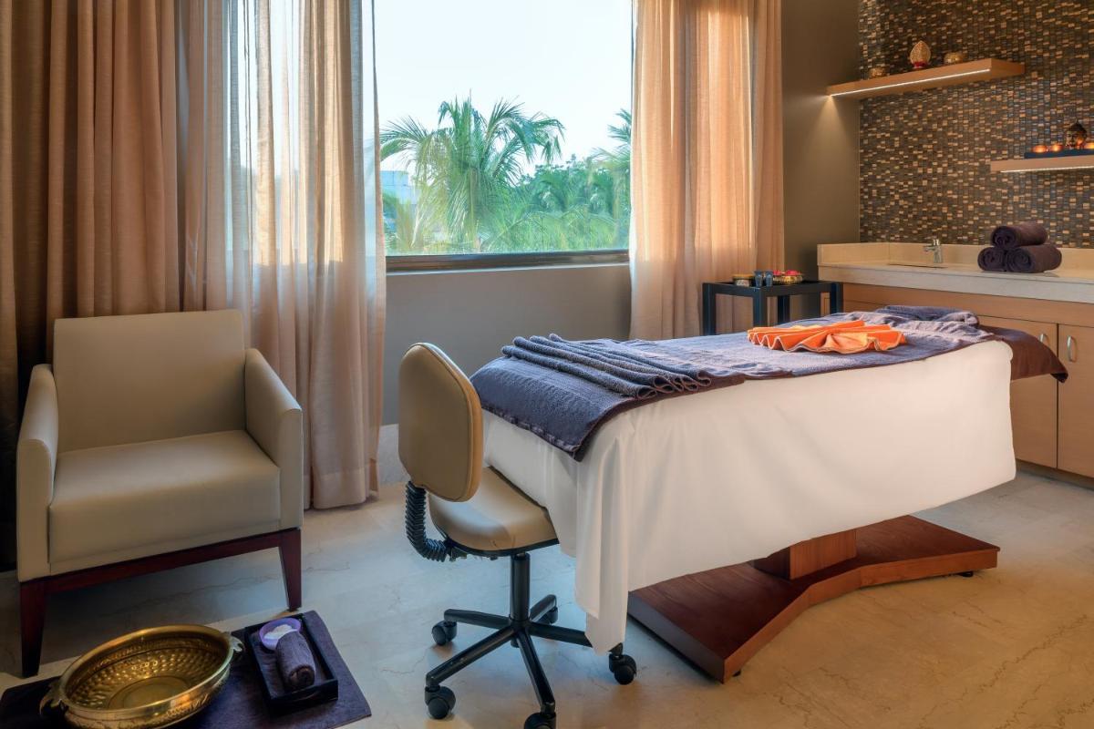a bedroom with a bed and a chair and a window at Feathers- A Radha Hotel, Chennai in Chennai