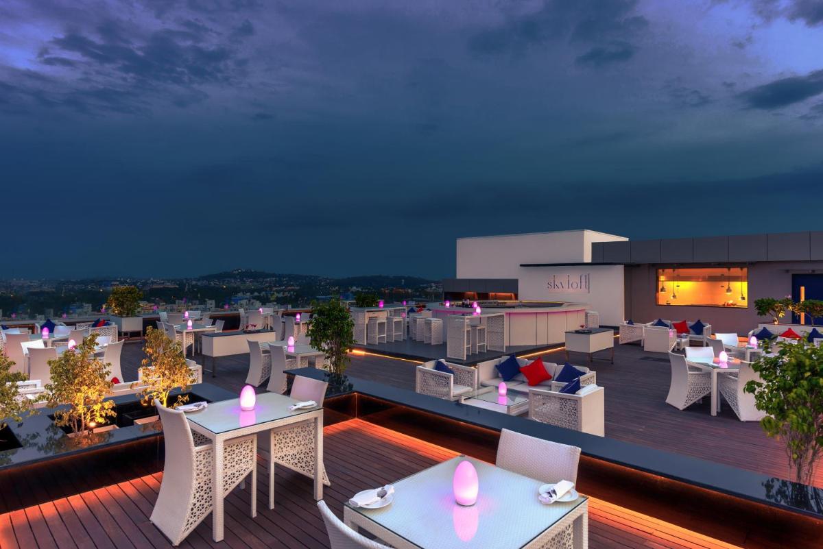 a view of a rooftop deck at night with tables and chairs at Feathers- A Radha Hotel, Chennai in Chennai