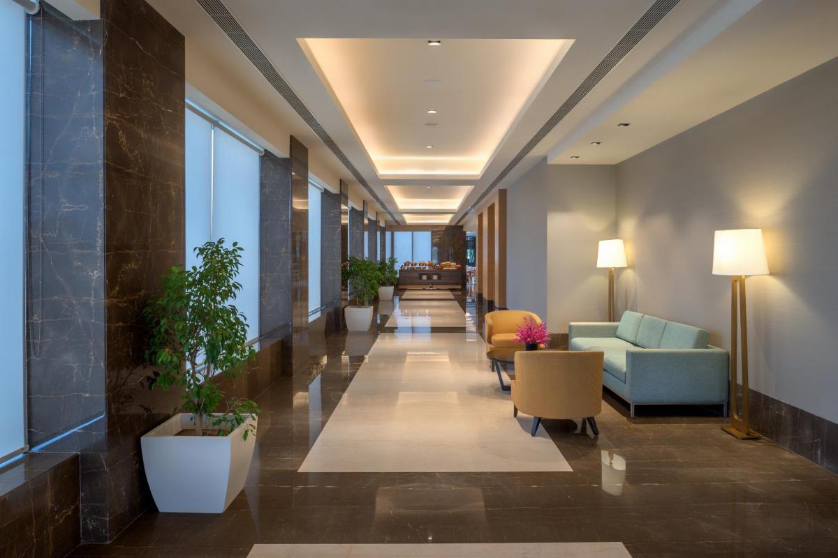 a hallway in a building with furniture and plants at Feathers- A Radha Hotel, Chennai in Chennai