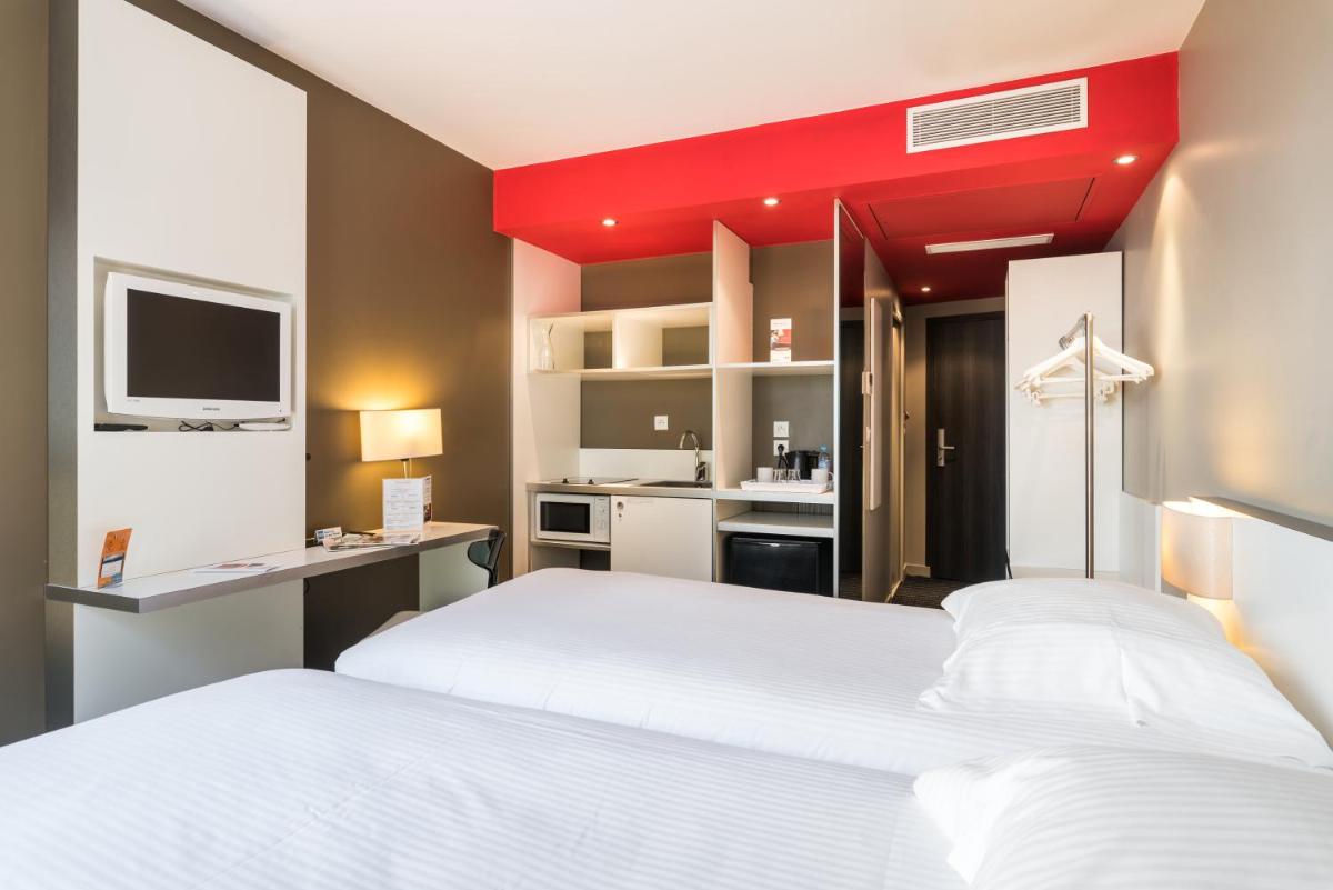une chambre avec deux lits blancs et un mur rouge dans l'établissement B&B HOME Lyon Centre Berthelot, à Lyon
