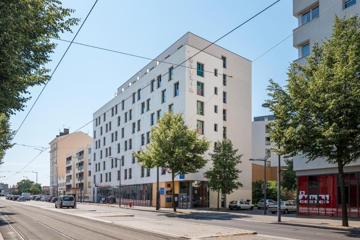 un grand immeuble blanc dans une rue de la ville dans l'établissement B&B HOME Lyon Centre Berthelot, à Lyon