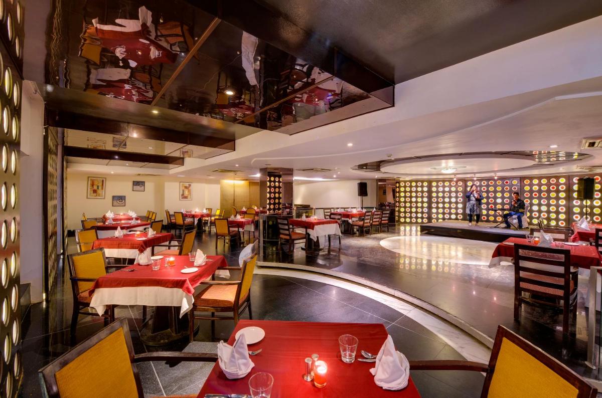 a restaurant with red tables and yellow chairs and a room at Pride Plaza Hotel, Ahmedabad in Ahmedabad