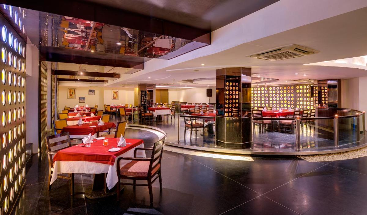 a restaurant with red tables and chairs in a room at Pride Plaza Hotel, Ahmedabad in Ahmedabad