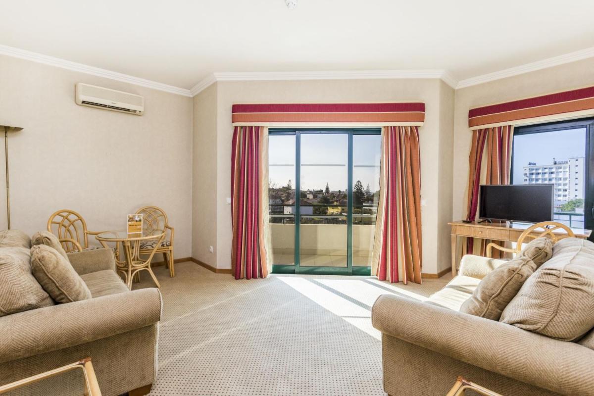 uma sala de estar com dois sofás e uma televisão em Riviera Hotel em Carcavelos