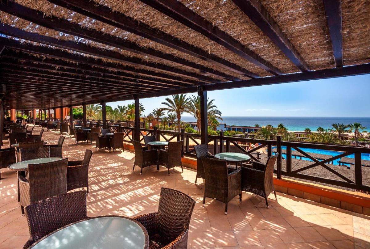 Un patio con mesas y sillas y vista al mar. en Occidental Jandía Playa, en Morro del Jable