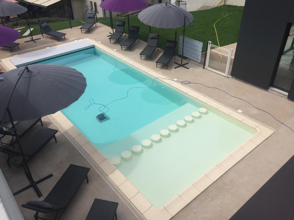 - une vue sur la piscine avec un parasol dans l'établissement Logis Hôtel et Spa Chez Camillou, à Aumont-Aubrac
