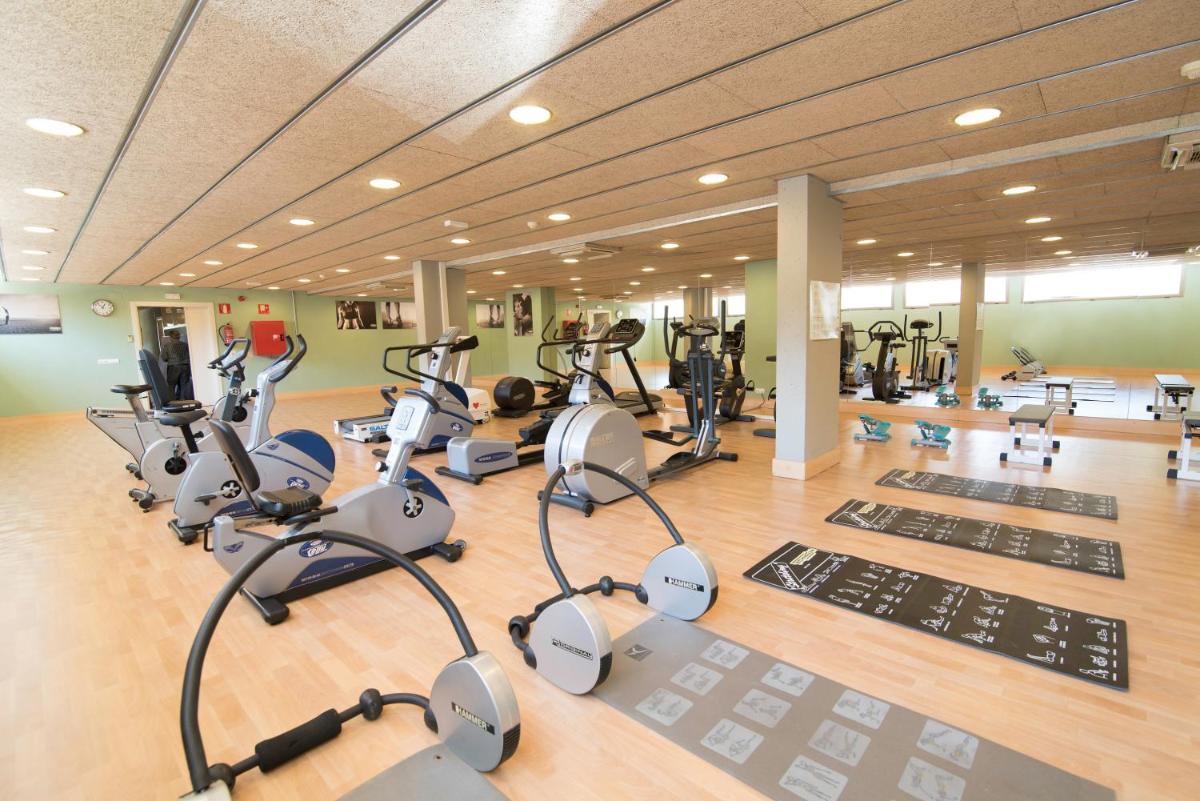un gimnasio con muchas cintas de correr y máquinas elípticas en Aparthotel Ciutat de Palol, en Platja d'Aro