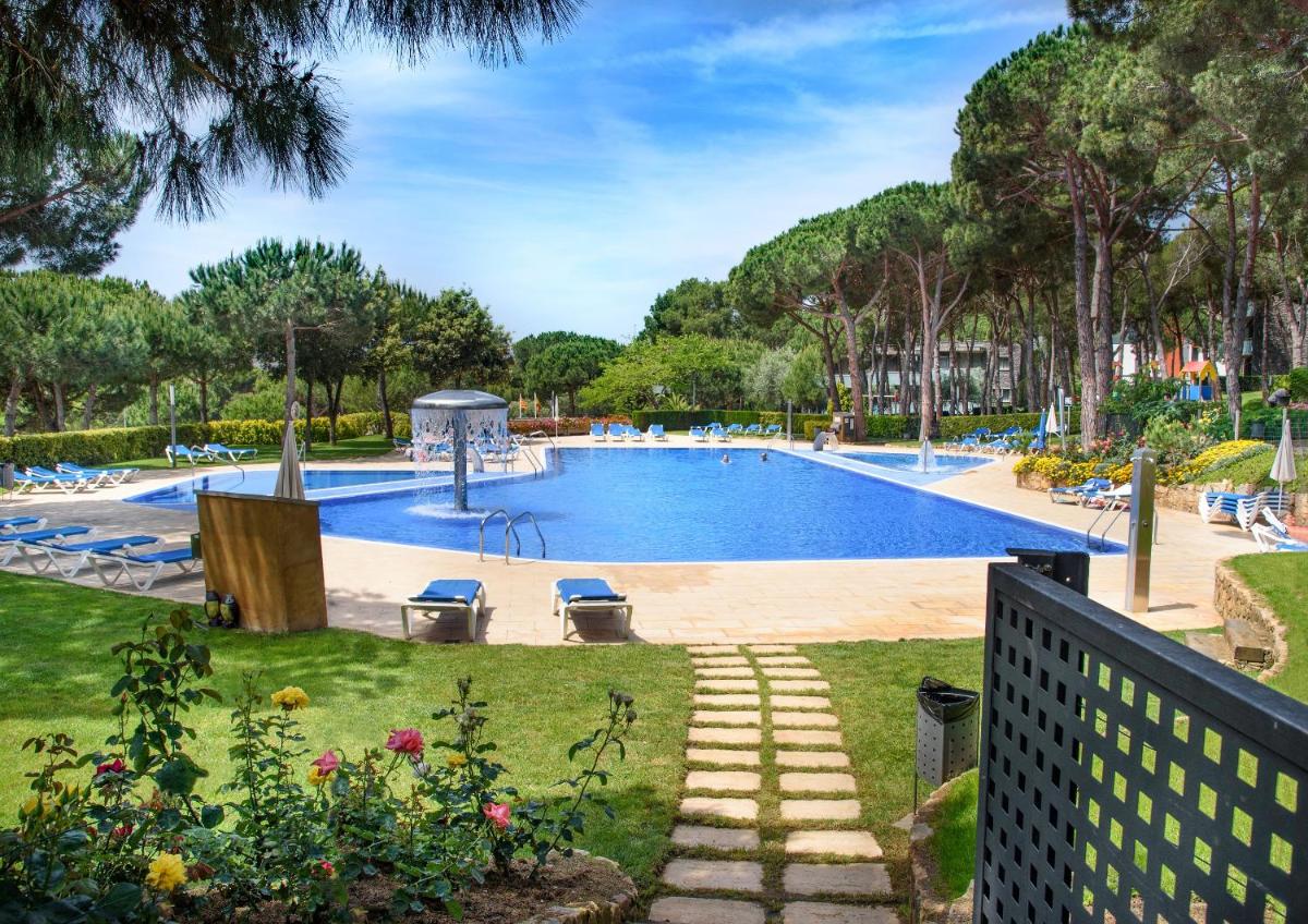 una gran piscina en un parque con árboles en Aparthotel Ciutat de Palol, en Platja d'Aro