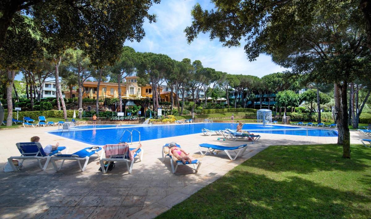 Un grupo de personas sentadas en sillas junto a una piscina. en Aparthotel Ciutat de Palol, en Platja d'Aro