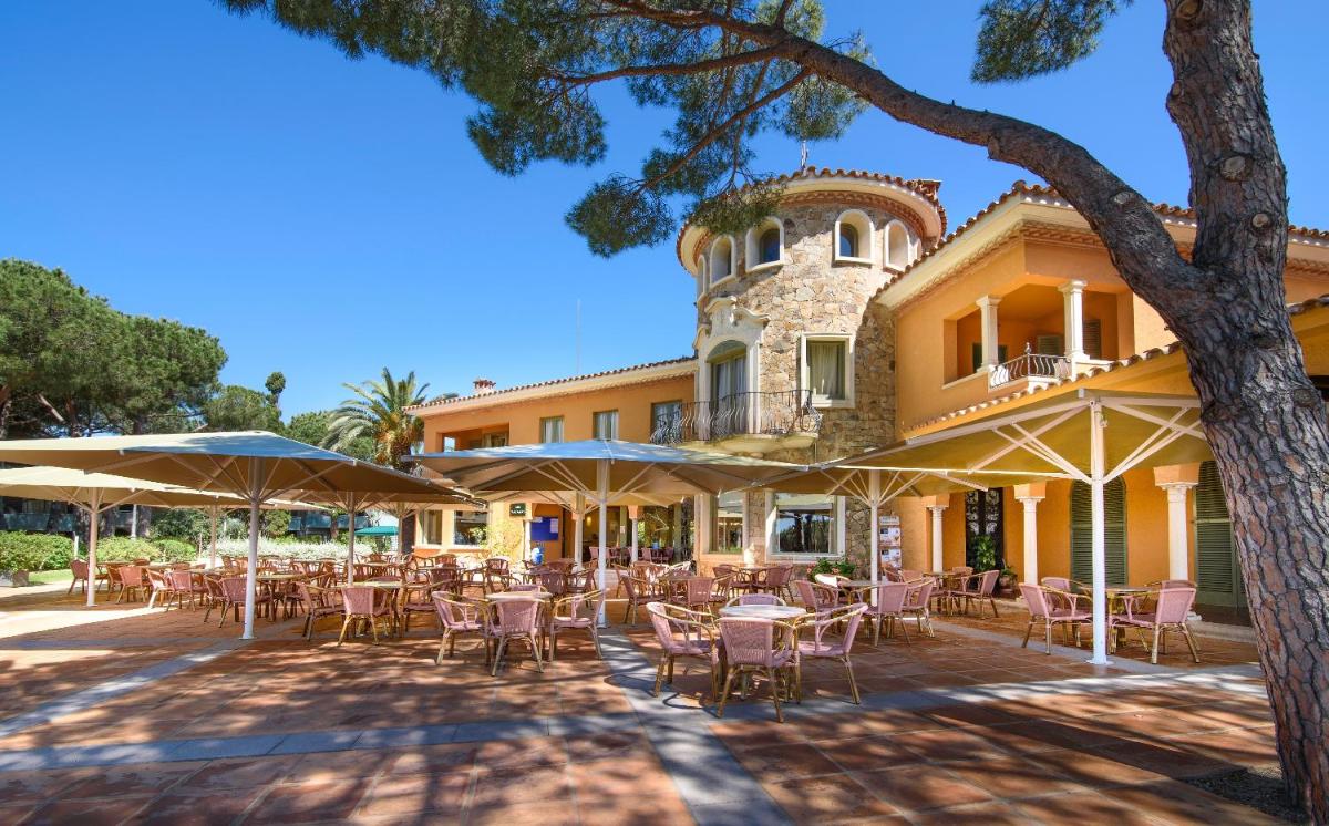 Un patio al aire libre con mesas y sillas frente a un edificio. en Aparthotel Ciutat de Palol, en Platja d'Aro