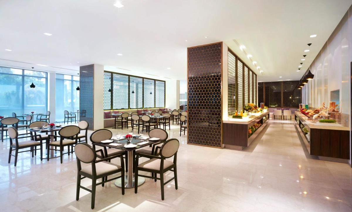 a restaurant with tables and chairs and a buffet at Vivanta Chennai IT Expressway OMR in Chennai
