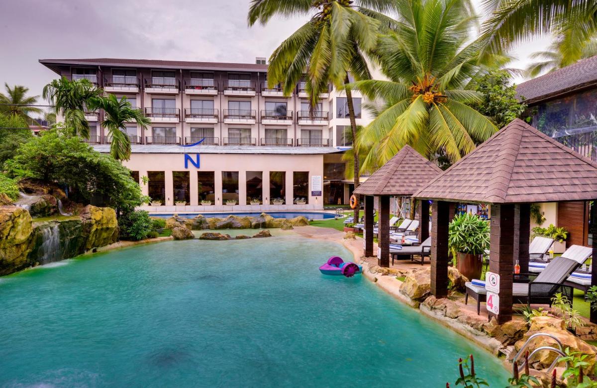 a swimming pool in front of a hotel at Novotel Goa Candolim in Candolim a swimming pool in front of a hotel at Novotel Goa Candolim in Candolim