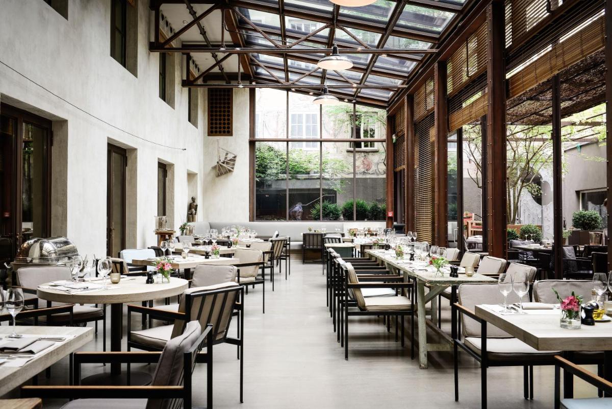 ein Esszimmer mit Tischen und Stühlen und Fenstern in der Unterkunft Hotel Bayerischer Hof in München