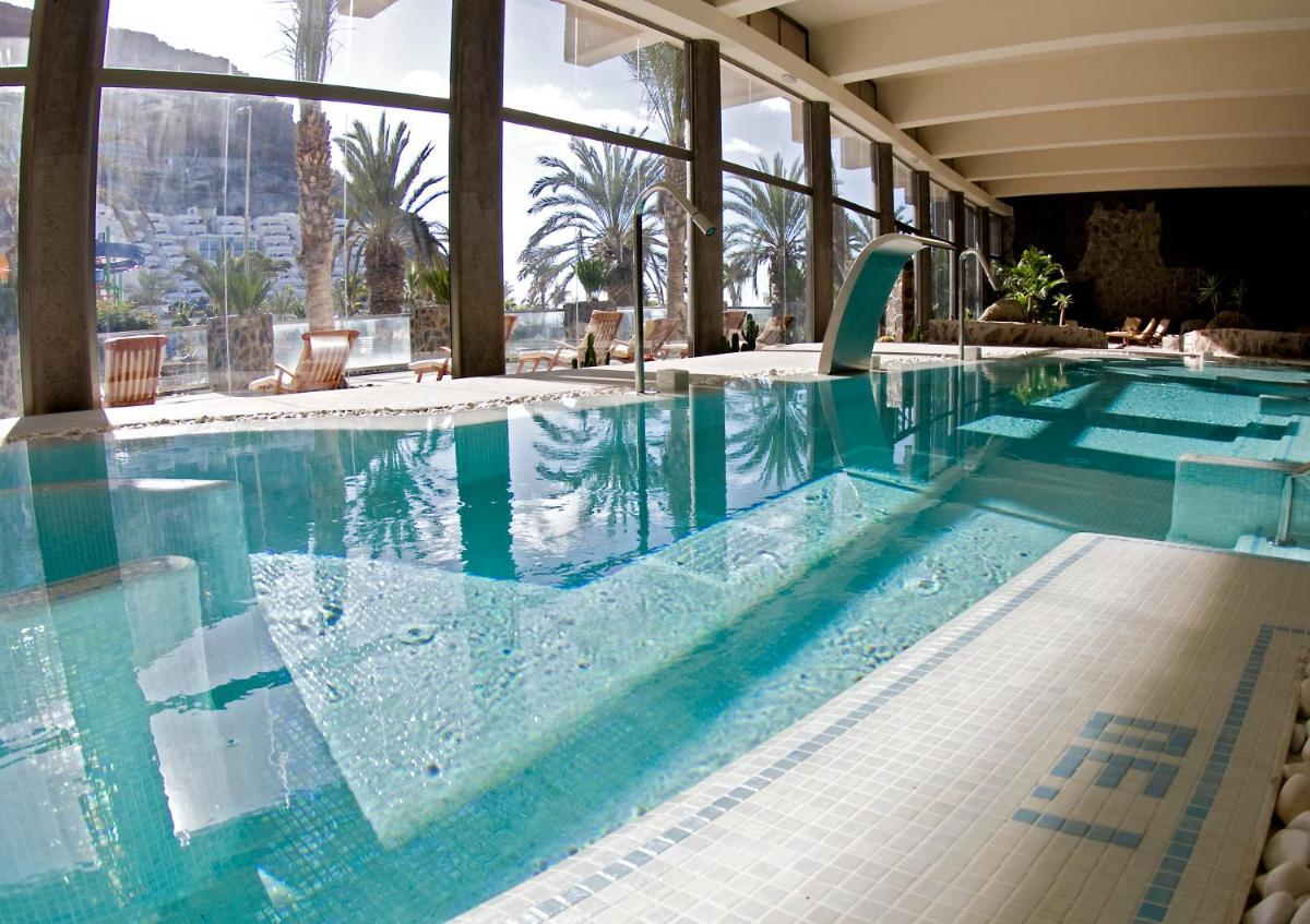 una piscina con agua azul en un edificio en Hotel LIVVO Costa Taurito & Aquapark, en Taurito