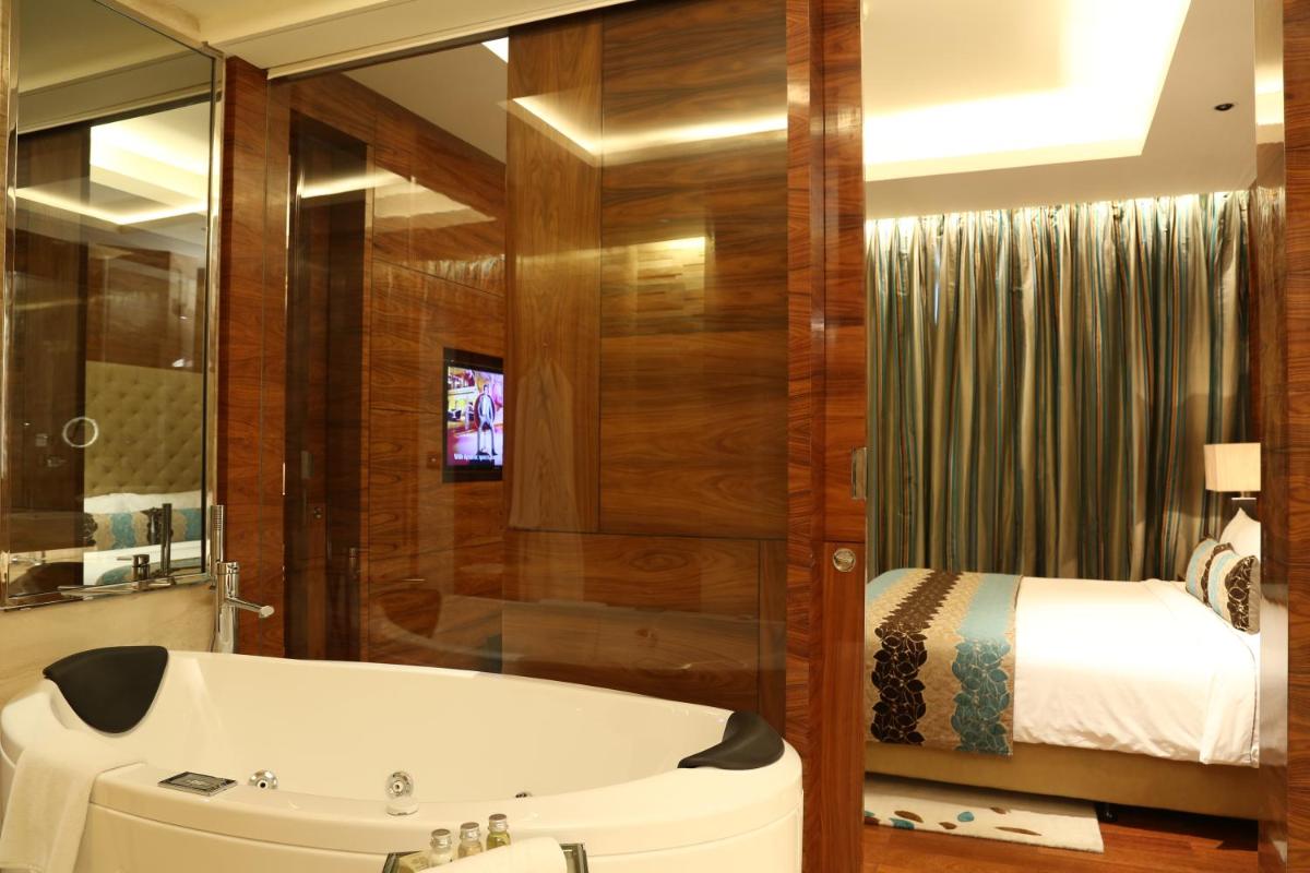 a bathroom with a tub next to a bed at Taj City Centre Gurugram in Gurgaon